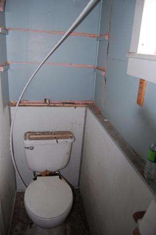 Small, unfinished bathroom with exposed wall framing.