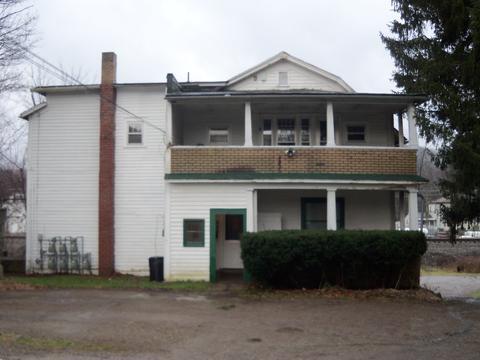 An old, two-story white house with a porch
